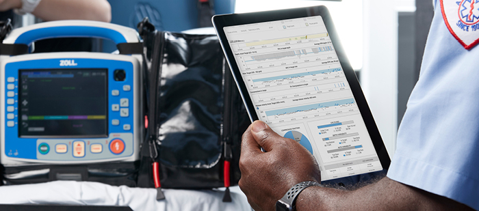 X Series Advanced monitor/defibrillator on gurney with patient while Paramedic reviews data on a tablet.